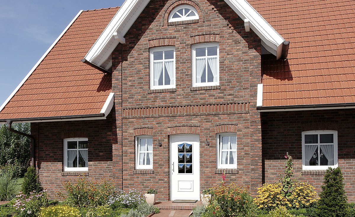 Verklinkertes Haus mit einer Haustür mit Ornament-Profilleisten und Buteznglas